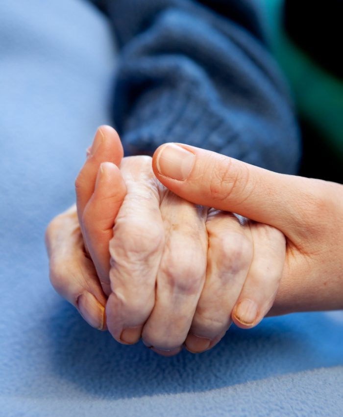 A young hand touches and holds an old wrinkled hand